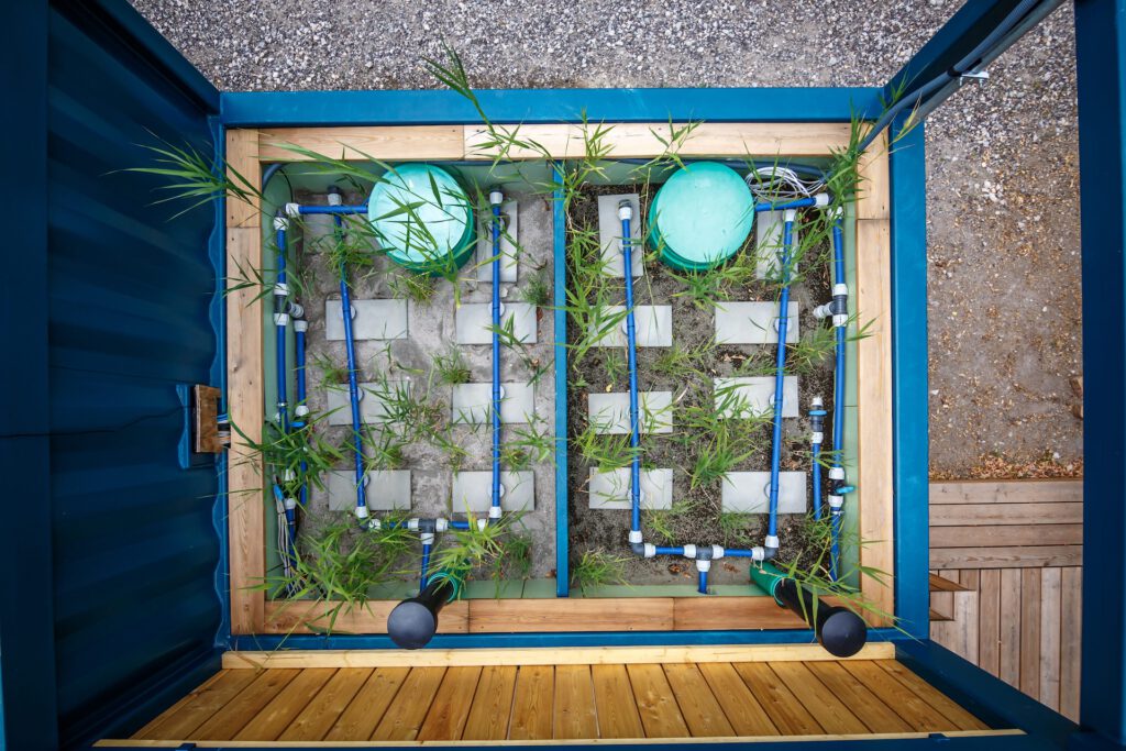 Modularer Container-Bodenfilter mit Rohrleitungssystem, Filtermedium und Schilfbepflanzung zur dezentralen Wasseraufbereitung. © J. Rettig, JULIAN RETTIG | FOTOGRAFIE