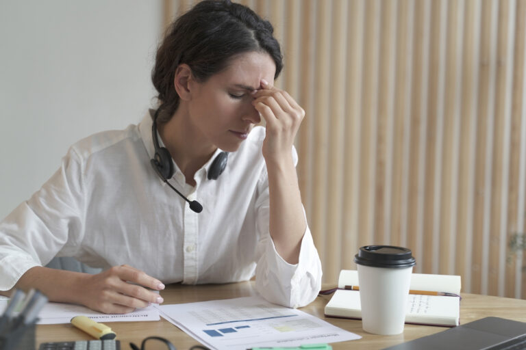 Tired spanish female home office worker massaging nose or inner corners of her eyes