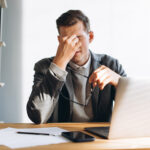 Modern man with glasses, office worker tired at work