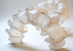 Künstlerische Darstellung eines biobasierten Soft-Roboters mit Kresling-Origami-Struktur: Die raffinierte Falttechnik ermöglicht flexible Bewegungen, gesteuert durch interne Fäden.