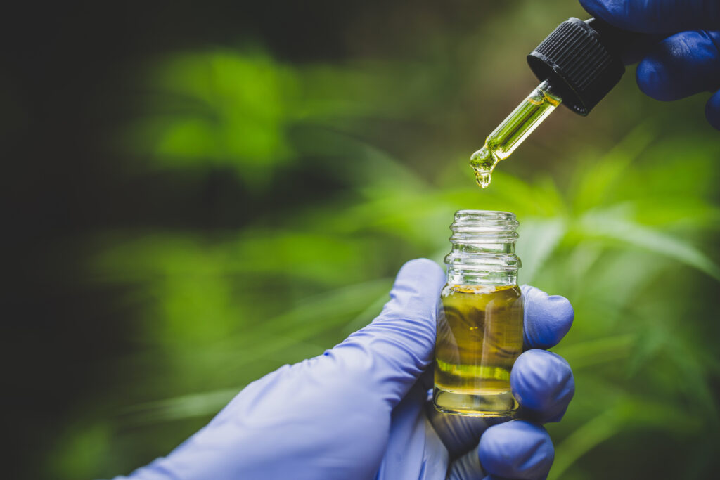 Hand holding bottle of Cannabis oil in pipette, Hemp oil, medica