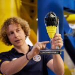 Projektingenieur Marvin Raupert mit einem Modell, das den 3D-Druckprozess veranschaulicht.
