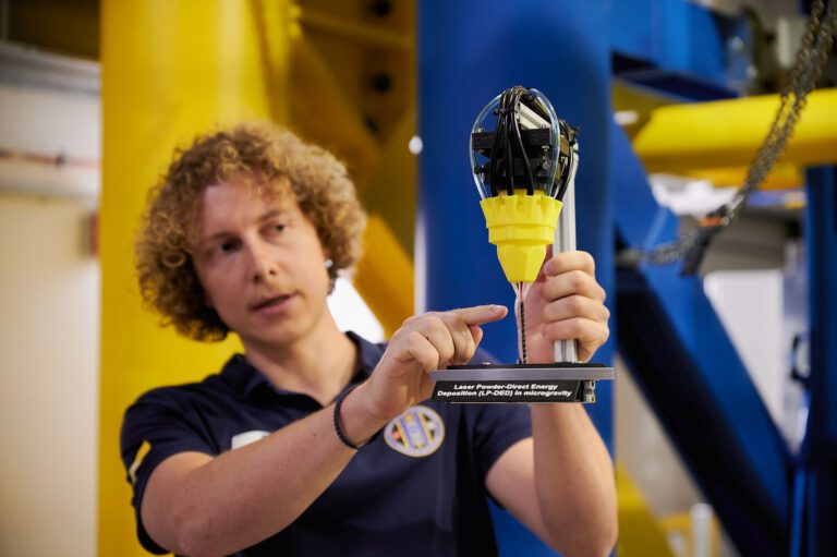 Projektingenieur Marvin Raupert mit einem Modell, das den 3D-Druckprozess veranschaulicht.