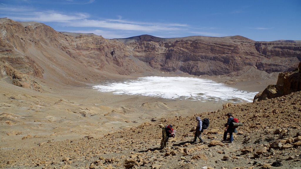 Blick in den Era-Kohor-Subkrater des Emi Koussi, dem höchsten Berg der Sahara: Auf dem Boden liegen helle Salzkrusten, Überreste eines prähistorischen Kratersees.