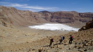 Blick in den Era-Kohor-Subkrater des Emi Koussi, dem höchsten Berg der Sahara: Auf dem Boden liegen helle Salzkrusten, Überreste eines prähistorischen Kratersees.