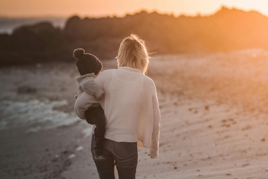 Mutter geht mit Kind am Strand spazieren