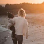 Mutter geht mit Kind am Strand spazieren
