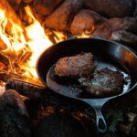 Fleisch wird in einer Pfanne über dem Feuer gebraten