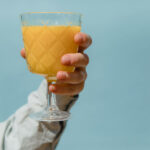Ein Glas Orangensaft in der Hand