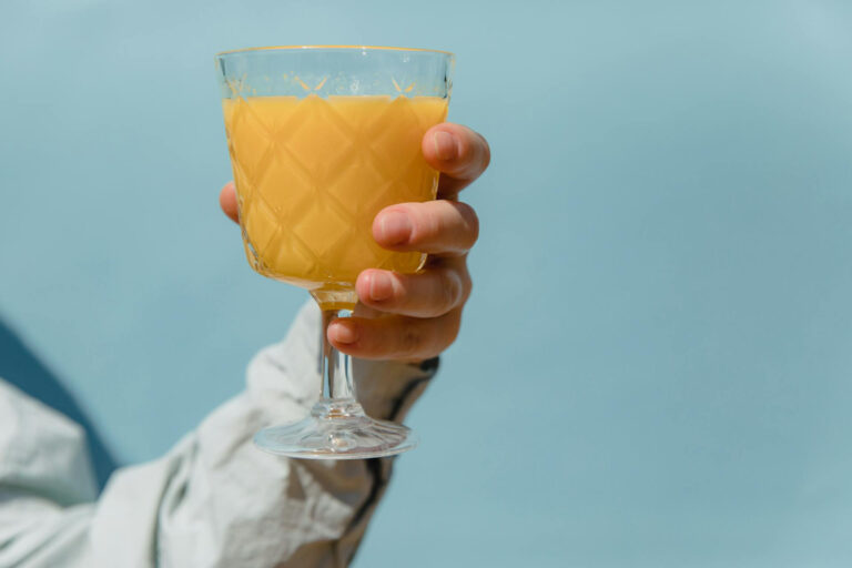 Ein Glas Orangensaft in der Hand