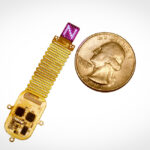 Ein dünnes, flexibles Gehirnimplantat liegt neben einer Münze zum Größenvergleich und sendet Lichtmuster aus, die Informationen direkt ins Gehirn übertragen.