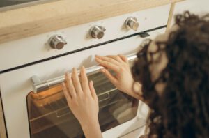 Frau schaut in den Ofen