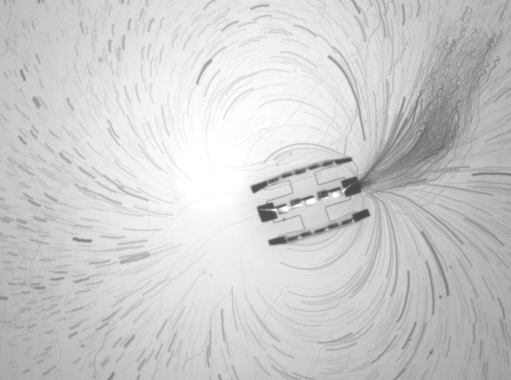Strömungen im Mikromaßstab sichtbar gemacht: Eine Zeitrafferprojektion zeigt die Bahnen feinster Partikel rund um einen Roboter mit drei gekoppelten Antriebseinheiten. © Lucas Hanson und William Reinhardt, University of Pennsylvania