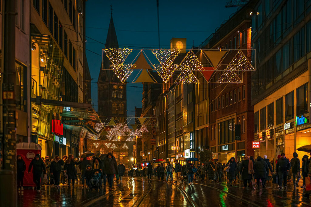 Menschen, die nachts eine Straße in Bremen zur Weihnachtszeit entlanggehen