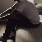 Mann sitzt auf dem Bett