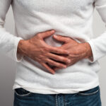 Person hält sich mit beiden Händen den Bauch