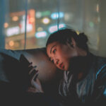 Frau am Handy auf der Couch