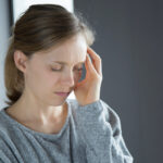 Frau massiert sich die Schläfe