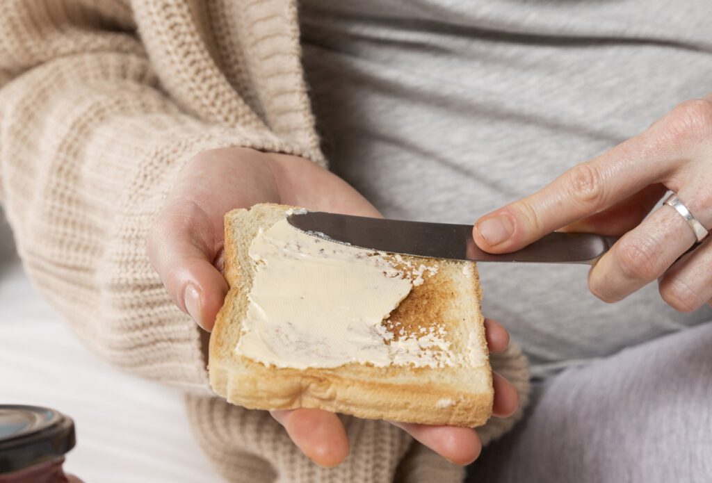 Frau schmiert sich Butter auf einen Toast