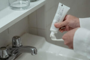 Frau macht Zahnpasta über einem Waschbecken auf die Zahnbürste