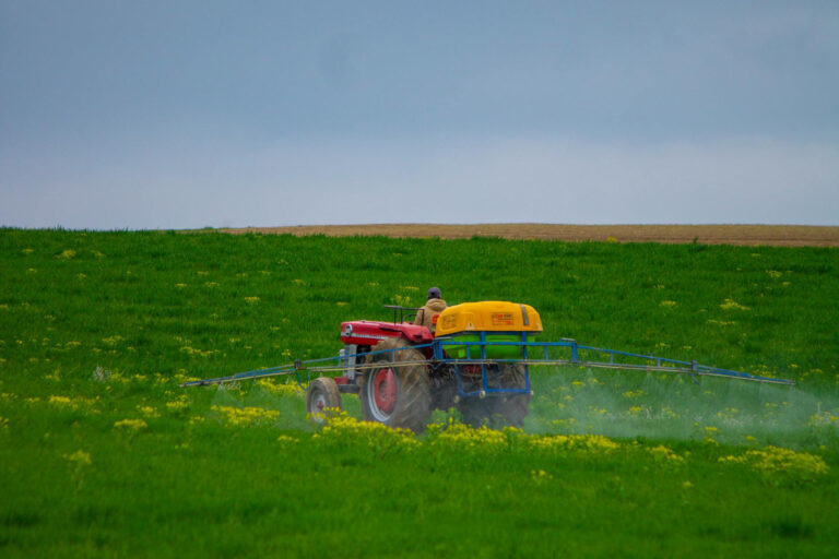 Ein Traktor fährt über ein Feld und versprüht Pestizide.