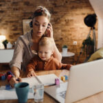 Mutter am Laptop mit Kind auf dem Schoß