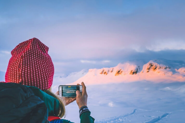 Frau mit Smartphone in verschneiten Bergen