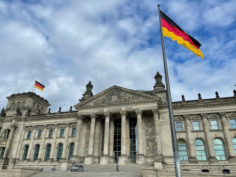 Der deutsche Bundestag mit Deutschlandfahnen von außen.