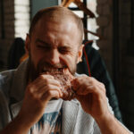 Mann beißt in ein Stück Fleisch