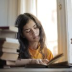 Junge Frau sitzt am Schreibtisch und lernt