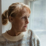 Ältere Frau schaut aus dem Fenster