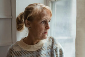 Ältere Frau schaut aus dem Fenster