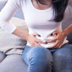 Junge Frau hält sich den Bauch