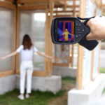 Auf dem Bildschirm eines Wärmescanners sind die Umrisse einer Frau zu sehen, die innerhalb eines Pavillons mit gekühlten Paneelen steht.