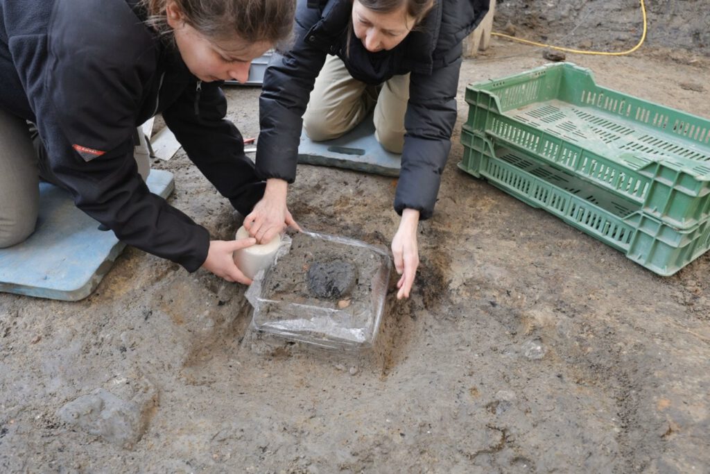 Sorgfältig im Erdblock geborgen: Restauratorinnen sichern das verkohlte römische Brot für weitere Analysen. © Kanton Aargau