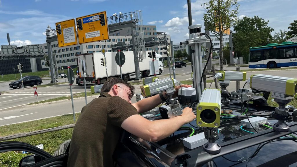 Autos, die um Ecken sehen können: TUM-Forscher Erik Leo Haß überprüft die Sensoren eines Testfahrzeugs an einer Kreuzung in Garching-Hochbrück. © Schmitz/TUM
