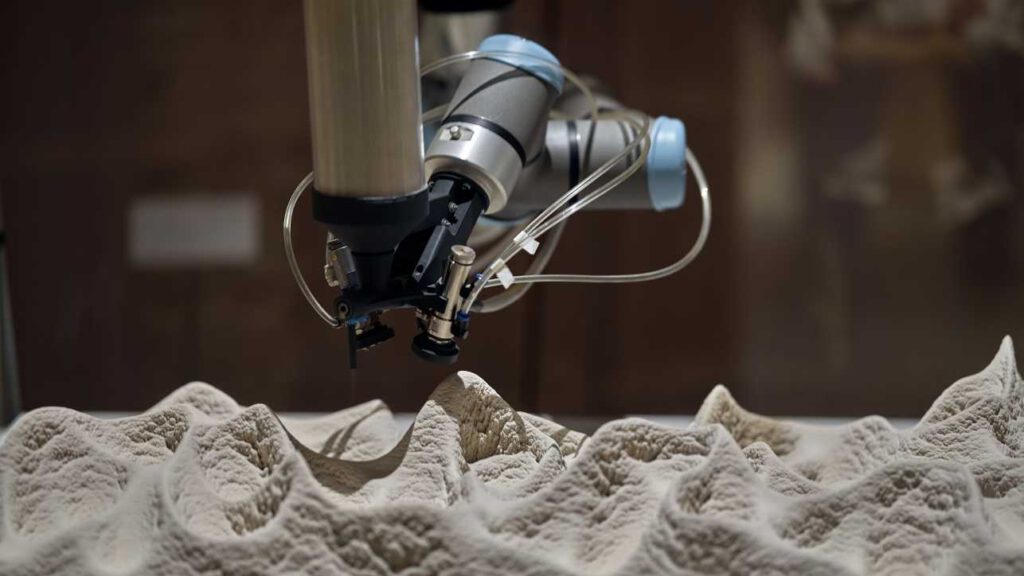 Ein Roboterarm trägt abwechselnd Bakterien, Stoffe zur Kalkbildung und Sand auf. So wächst Schicht für Schicht eine feste Struktur, bei der Kalk die Sandkörner miteinander verbindet. © Gerhard Bliedung / ETH Zürich