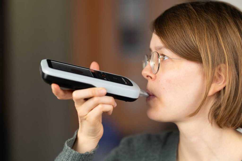 Eine Nutzerin führt mit dem smartphoneunterstützten Aceton-Atemanalysator eine Messung durch. © Alivion AG