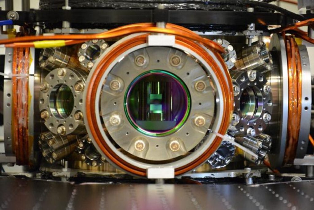 Im Herzen des Experiments halten zwei gekrümmte Spiegel Photonen in einer optischen Kammer fest. Zwischen ihnen erzeugen Laser extrem kalte Quantengase – die Grundlage für das quantum-optische Spin-Glas.