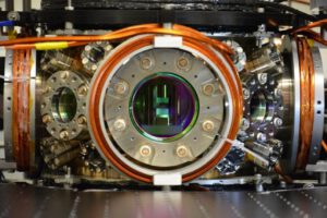 Im Herzen des Experiments halten zwei gekrümmte Spiegel Photonen in einer optischen Kammer fest. Zwischen ihnen erzeugen Laser extrem kalte Quantengase – die Grundlage für das quantum-optische Spin-Glas.