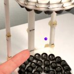 Ein neuer Zeitkristall schwebt auf einem Polster aus Schall: Das Bild zeigt ein Teilchen, das in einem 15 Zentimeter hohen, 3D-gedruckten Aufbau von Lautsprechern in der Luft gehalten wird.