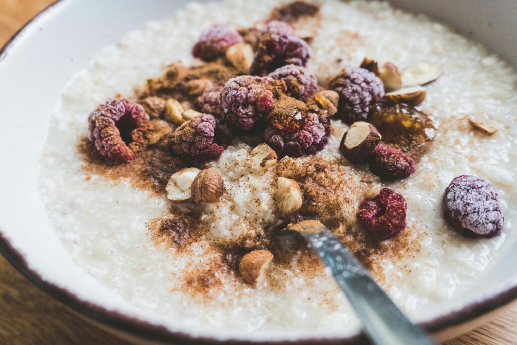 Haferbrei mit Tiefkühlbeeren, Nüssen und Zimt: Ein einfaches Frühstück liefert Ballaststoffe, Vitamine und gesunde Fette – ohne teure Spezialprodukte.