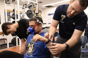 Wie genau misst die Smartwatch wirklich? FIU-Forscher Jason Kostrna legt einem Teilnehmer die Uhr an, während ein Stoffwechselmessgerät den tatsächlichen Kalorienverbrauch erfasst. © Taimy Alvarez / Florida International University