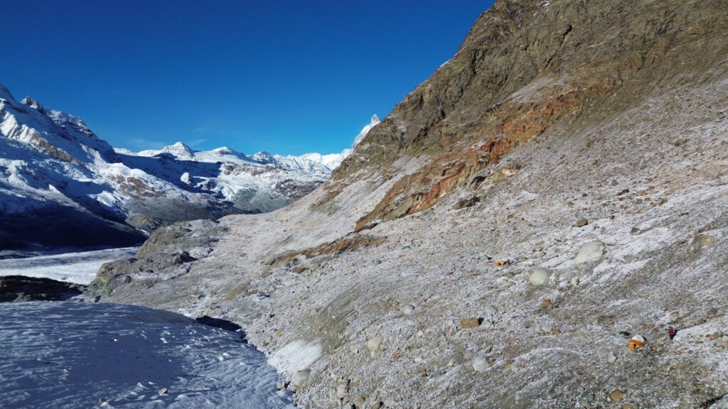 Gornergletscher mit umliegender Berglandschaft; am unteren rechten Bildrand steht ein Zelt mit Messgerät.