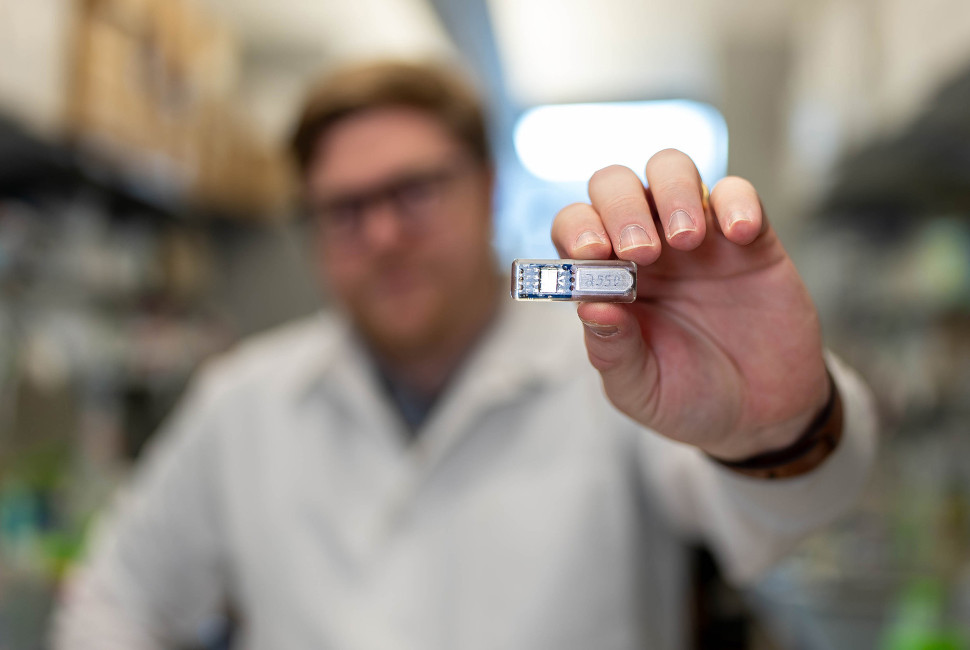 Mann hält Implantat in die Kamera