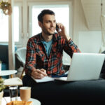 Mann im Homeoffice mit Laptop, Handy und Notizblock