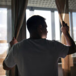 Junger Mann steht am Fenster