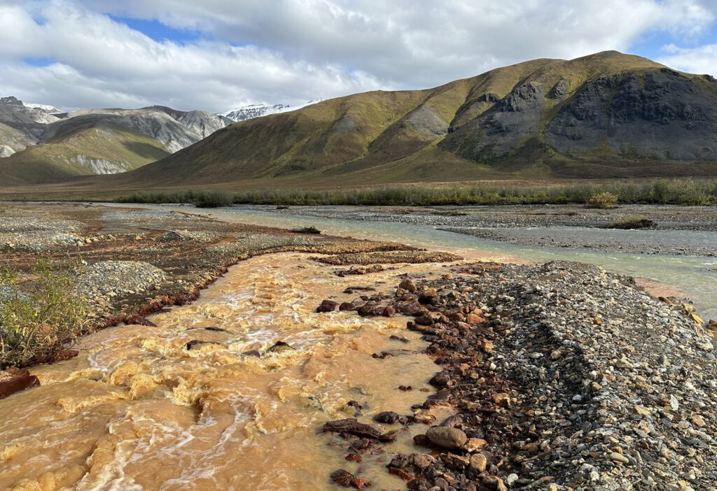 Ein rostorange verfärbter Sickerbereich in Alaska zeigt, wie stark auftauender Permafrost die Wasserchemie verändern kann. © Taylor Evinger/UC Davis.