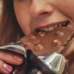 Frau beißt in ein Stück Schokolade