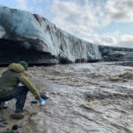 Eine Wissenschaftlerin nimmt am Gletscherende eine Wasserprobe aus dem Gletscherfluss Svalbreen. © Gabrielle Kleber (UiT, iC3)